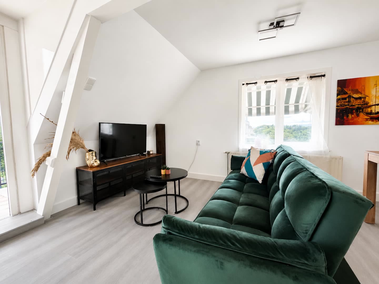Woonkamer van het appartement met groene velours bank en tv