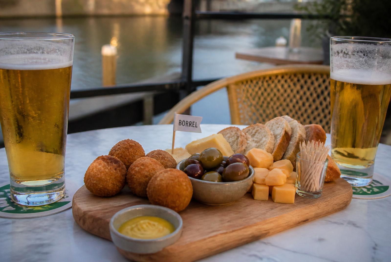 Borrelplank met bier aan het water (sfeerbeeld — vervangbaar)