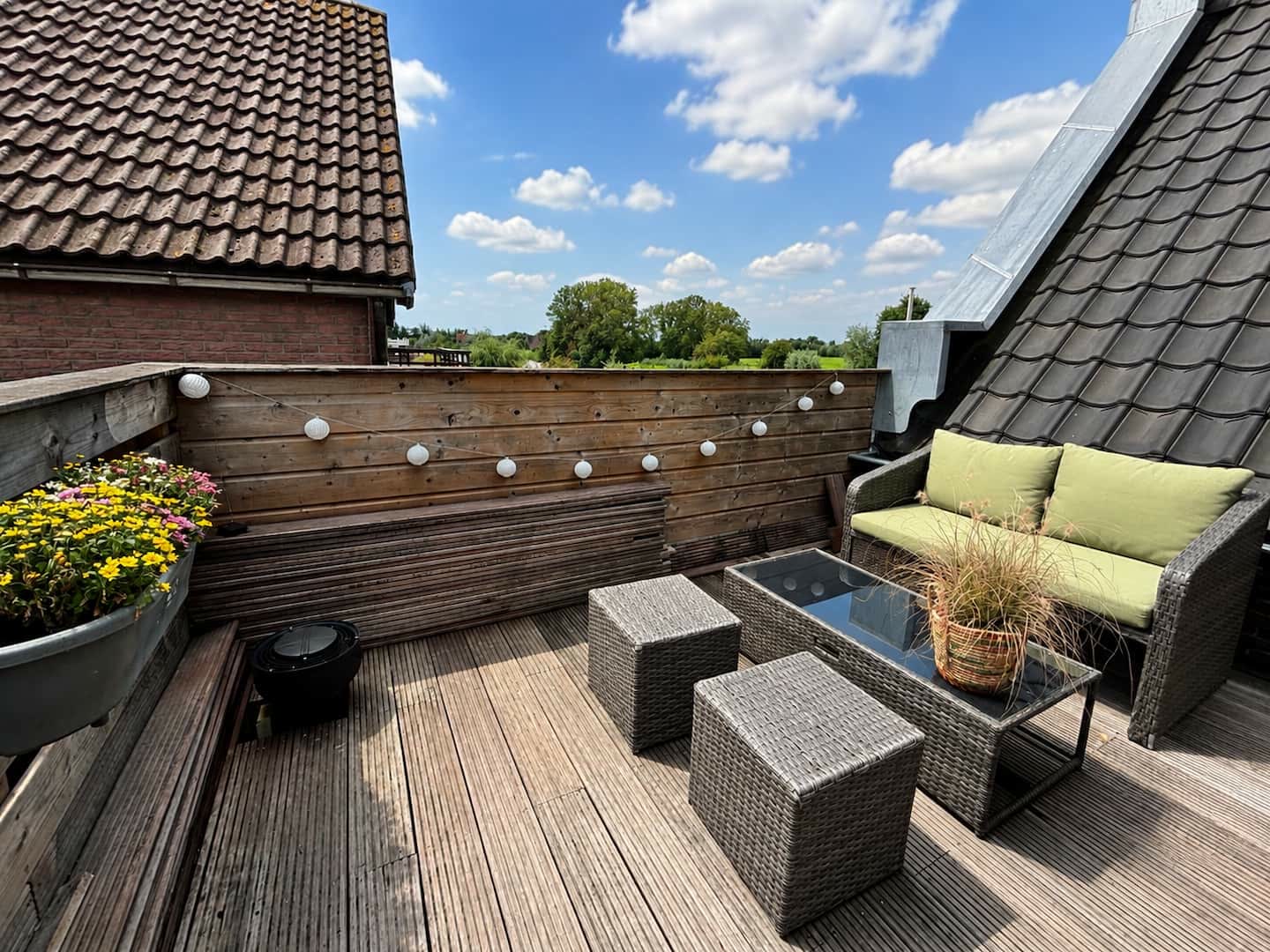 Privé-dakterras met loungeset, planten en uitzicht over de daken