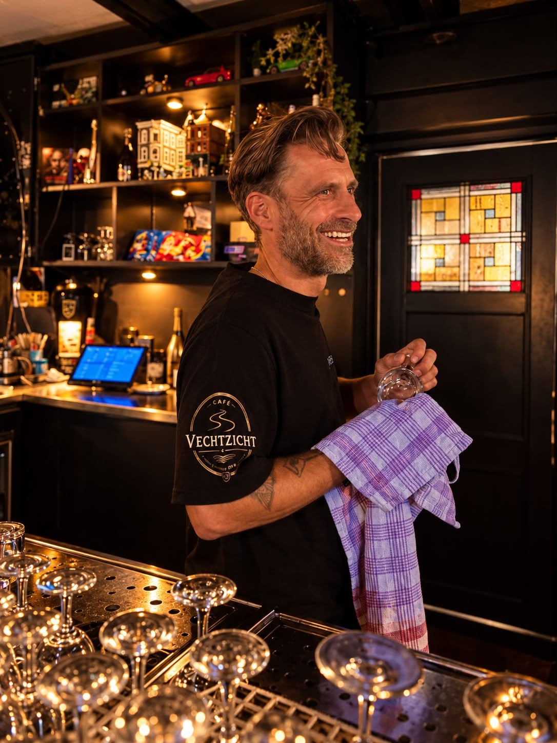 Barman van Café Vechtzicht die achter de bar een glas afdroogt